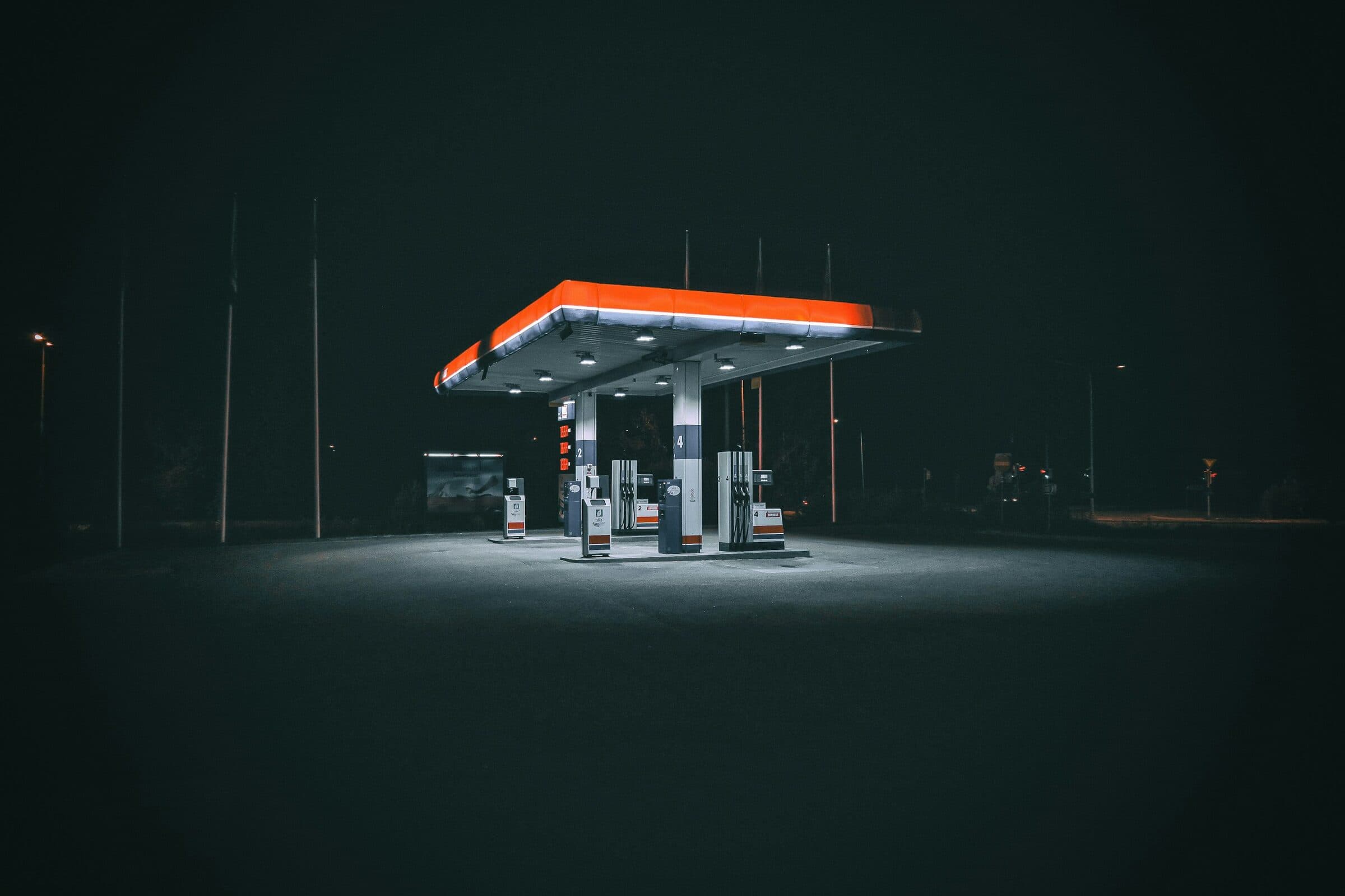 A lone gas station canopy glowing in the fog at night.